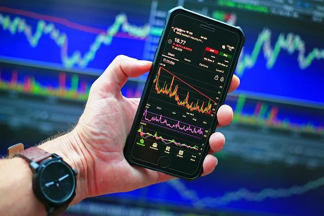 photo of a man holding a phone showing with stock charts
